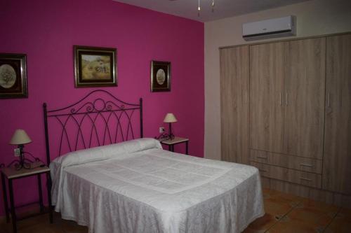 ヘレス・デ・ロス・カバジェロスにあるEl Manantialの紫の壁のベッドルーム1室(ベッド1台付)