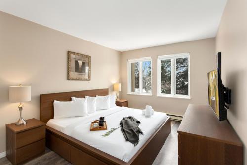 a bedroom with a bed and a desk and two windows at Tremblant Rocher Soleil Ski In Ski Out 2 Bedroom in Mont-Tremblant