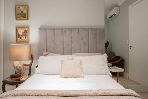 1 dormitorio con 1 cama grande con almohadas blancas en Casa Clássica no Mont Serrat, en Porto Alegre