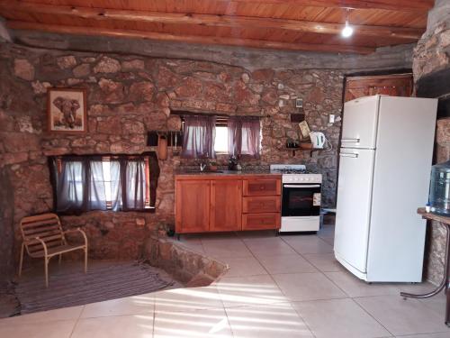 a kitchen with a white refrigerator and a stone wall at La Inspiración - Casa Serrana in Tanti