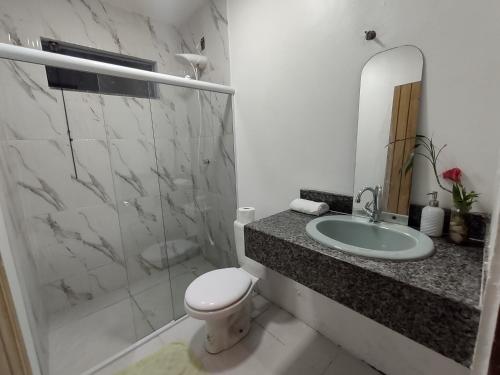 La salle de bains est pourvue de toilettes, d'un lavabo et d'une douche. dans l'établissement Casa Aroeira Pousada, à Ilhéus