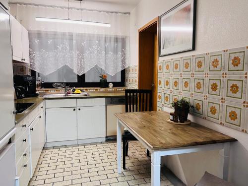 a kitchen with white cabinets and a wooden table at Apartments "Lichtenstein Valley" in Unterhausen