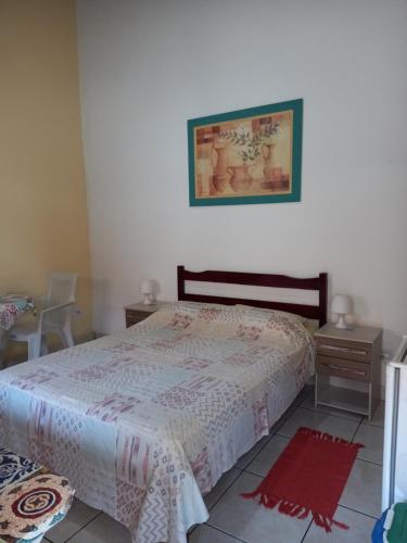 1 dormitorio con 1 cama y 2 mesitas de noche en Maranata Suítes - 2 minutos de carro até o mar, en Peruíbe