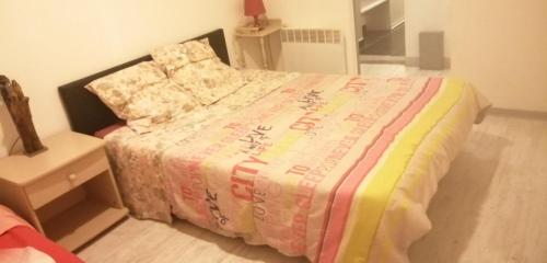 Un dormitorio con una cama con una manta de colores. en PETIT APPARTEMENT, en Perpiñán