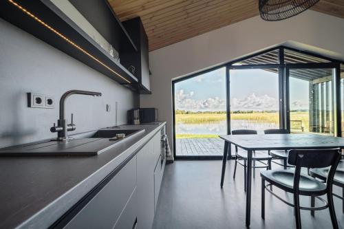 a kitchen with a table and chairs and a large window at Lielpīles in Radziņciems
