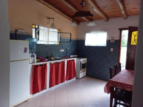 una cocina con electrodomésticos blancos y toallas rojas en la encimera en cabañas fátima en Villa Las Rosas
