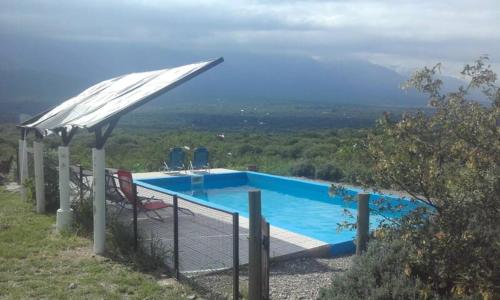 a swimming pool with a white umbrella and chairs at cabañas fátima in Villa de Las Rosas
