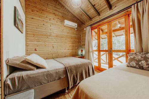 two beds in a room with wooden walls at Morada Guarda Explorer 01 in Guarda do Embaú