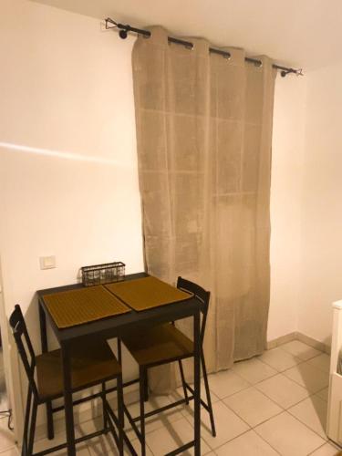 - une table à manger avec 2 chaises et un rideau dans l'établissement Au coeur d'Anglet, Studio Oihana - Plage et Biarritz à 10 min, à Anglet