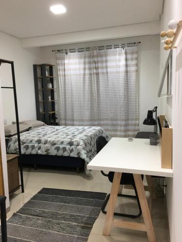 1 dormitorio con cama, mesa y escritorio en Loft próximo a UFMS, en Campo Grande
