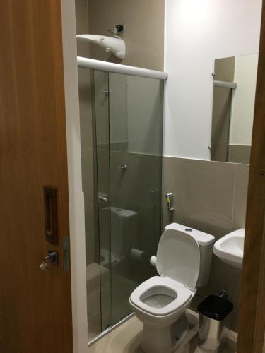 a bathroom with a toilet and a glass shower at Loft próximo a UFMS in Campo Grande