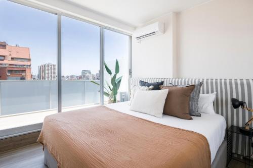 a bedroom with a large bed with a large window at Top Rentals Belgrano in Buenos Aires