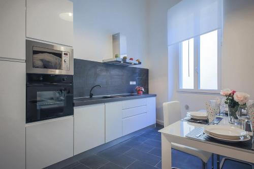 フィレンツェにあるApartments Florence Pandolfini Suiteの白いキャビネット、シンク、テーブル付きのキッチンが備わります。
