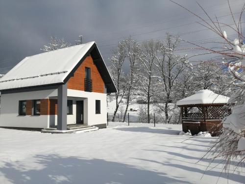una pequeña casa en la nieve con un cenador en Domek nad potokiem, en Grywałd