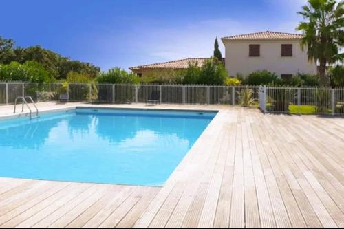 une piscine avec une terrasse en bois et une maison dans l'établissement Appartement Lena 6 pers piscine 500 m plage, à Sainte-Lucie de Porto-Vecchio