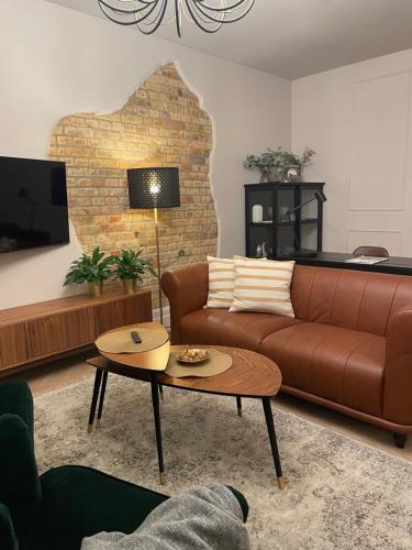 sala de estar con sofá marrón y mesa en Lindens apartments in the heart of the city, en Panevėžys