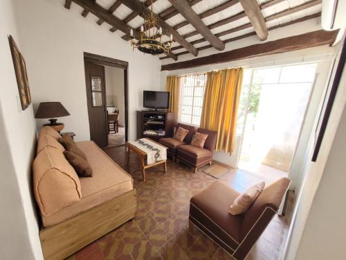 a living room with a couch and chairs and a tv at Casa Sarmiento in San Francisco del Monte de Oro
