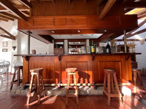 a bar with four wooden stools in a room at LA CURVA Casa de Playa in Villa Gesell