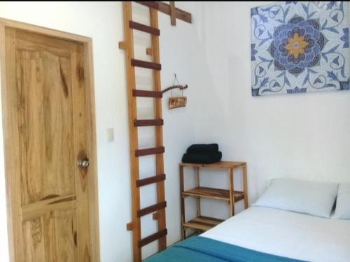 1 dormitorio con una escalera de madera junto a una cama en Portón Azul en Montañita