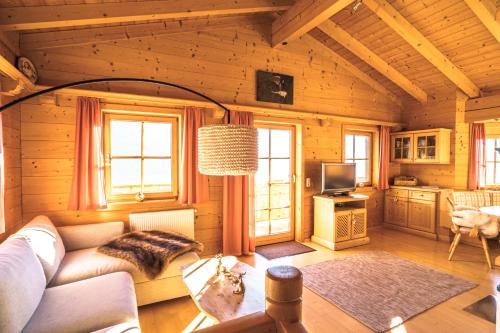 a living room with a couch and a tv in a cabin at Chalet Obenland Panorama Aussicht Kitzbühler Alpen in Bramberg am Wildkogel