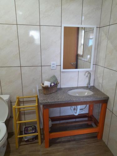 uma casa de banho com um lavatório, um espelho e um WC. em Refúgio da Mata Atlântica Sobrado Centenário em Torres