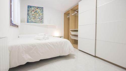 a white bedroom with a bed and a mirror at Casa Recogidas - Apartamentos Aloha Toledo in Toledo