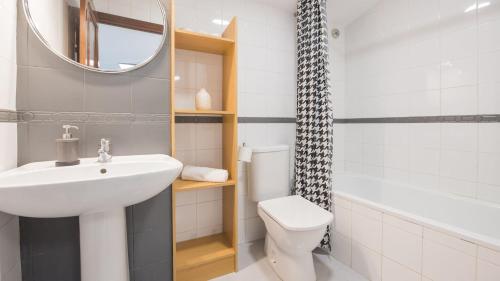 a bathroom with a sink and a toilet and a mirror at Casa Recogidas - Apartamentos Aloha Toledo in Toledo