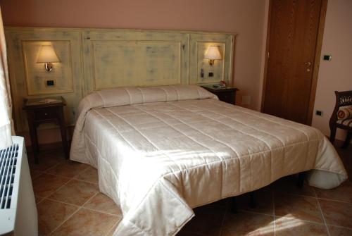 a bed in a bedroom with two tables and two lamps at Albergo La Foresteria in Bettolle