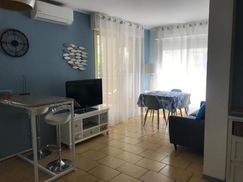 een woonkamer met een tv en een tafel met stoelen bij Blue Shades in Bordighera