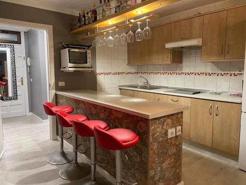 uma cozinha com um balcão com bancos vermelhos em Moderno apartamento al lado del mar em Tacoronte