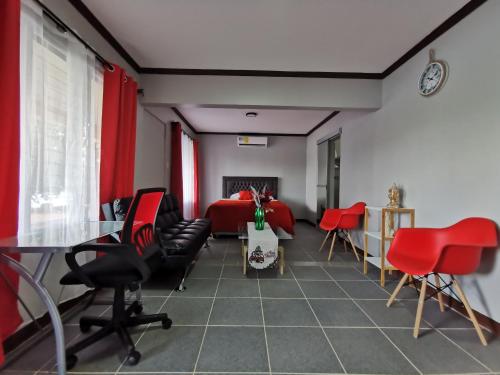 Habitación con sillas rojas y cama roja. en Hotel Puerto San Luis, en Tilarán