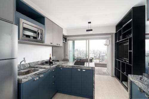 una cocina con armarios azules y una gran ventana en River One 2303 - Luxury Studio, en São Paulo