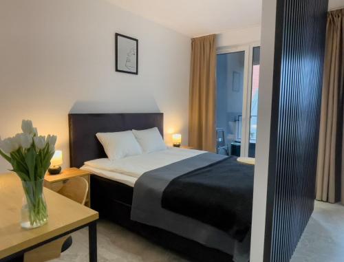una habitación de hotel con una cama y un jarrón de flores en URBAN APARTMENTS PREMIUM DOWNTOWN Opolska 10 No 90 with 2 GARAGES, en Katowice