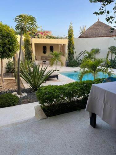 a villa with a swimming pool and palm trees at Villa Le Petit Paradis Saly Boutique Hotel in Ngaparou