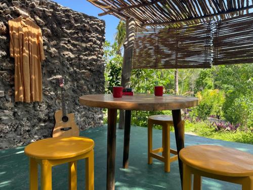 a table and two stools with cups and a guitar at Kameleon Blue in Kizimkazi