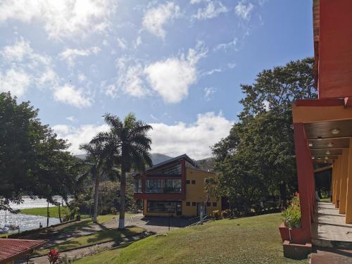 a house with a palm tree in front of a building at Hotel Puerto San Luis in Tilarán