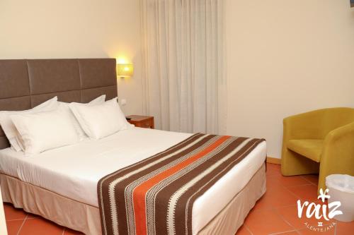 a hotel room with a bed and a chair at Raiz Alentejana II in Reguengos de Monsaraz