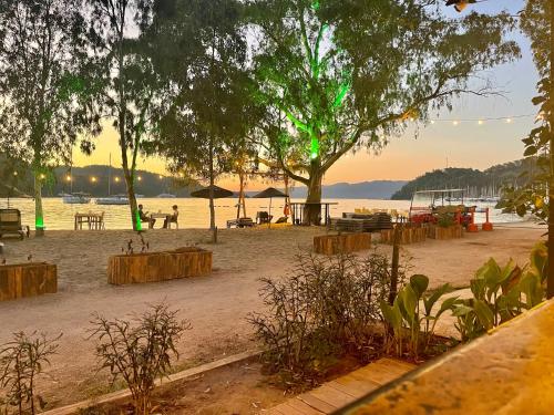 a beach with picnic tables and trees and the water at Marimare Beach & Bungalow in Marmaris
