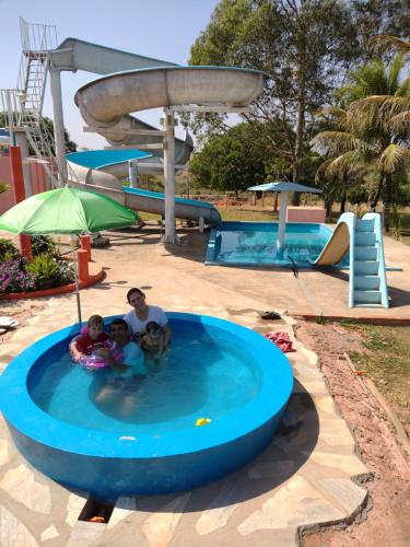 a man and two children in a pool at a water park at Camping e Pousada Buritis Park 