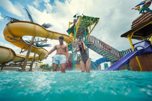 um homem e uma mulher de pé na água num parque aquático em Apartamento vacacional - disfruta playa y toboganes a 32km de la ciudad em ArraijÃ¡n