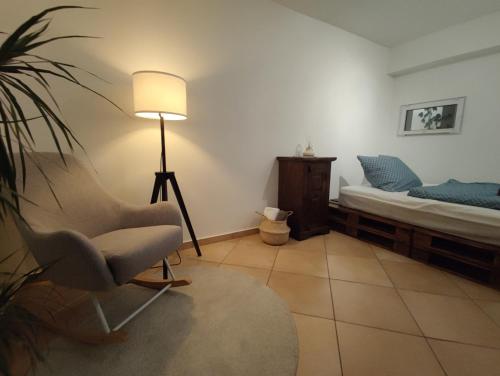 a bedroom with a bed and a chair and a lamp at ZEN Apartment - spacious for 7 - central - kitchen in Offenbach