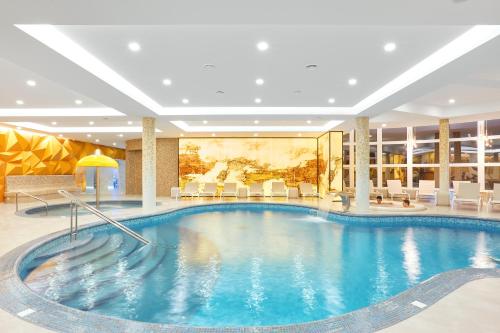 a pool in a hotel lobby with chairs and tables at GORGANY resort & SPA in Yablunytsya