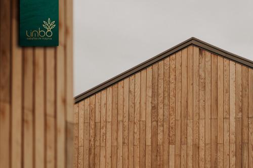 a wooden building with a green sign on it at Limbo Cabañas de Malpica in Malpica