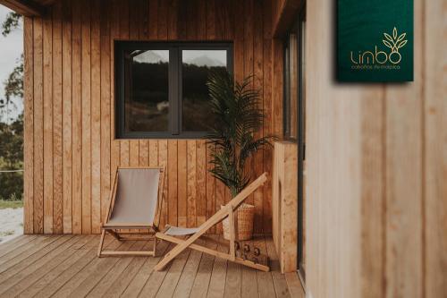 a wooden porch with a chair and a plant at Limbo Cabañas de Malpica in Malpica