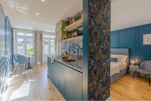 a kitchen with blue cabinets and a living room with a bed at As Vizinhas Boutique Apartments in Porto