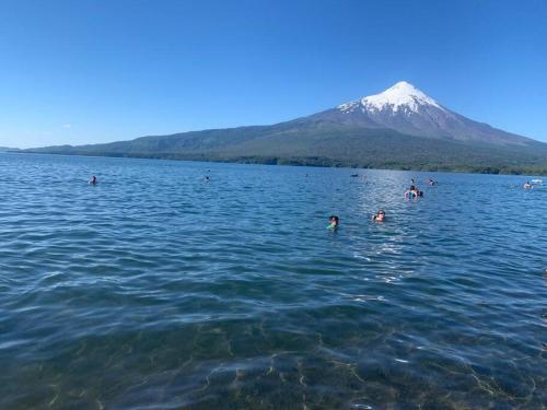 people swimming in a lake with a mountain in the background at Cabaña El Caballo Blanco in Llanquihue