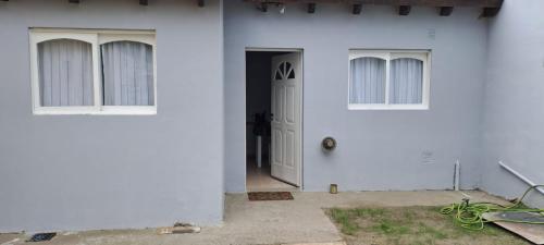 uma casa branca com uma porta branca e janelas em La casita em El Calafate