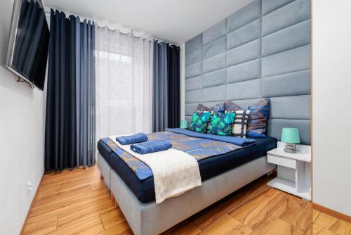 a bedroom with a large bed with a blue headboard at Apartament Glamour Kraków in Krakow