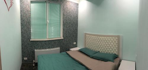 a bedroom with a bed with green pillows and a window at Ashtarak-2 LUX Apartment in Ashtarak