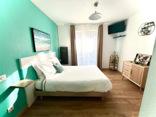 um quarto com uma cama e uma parede azul em Studio avec piscine aux portes d’Honfleur em Honfleur